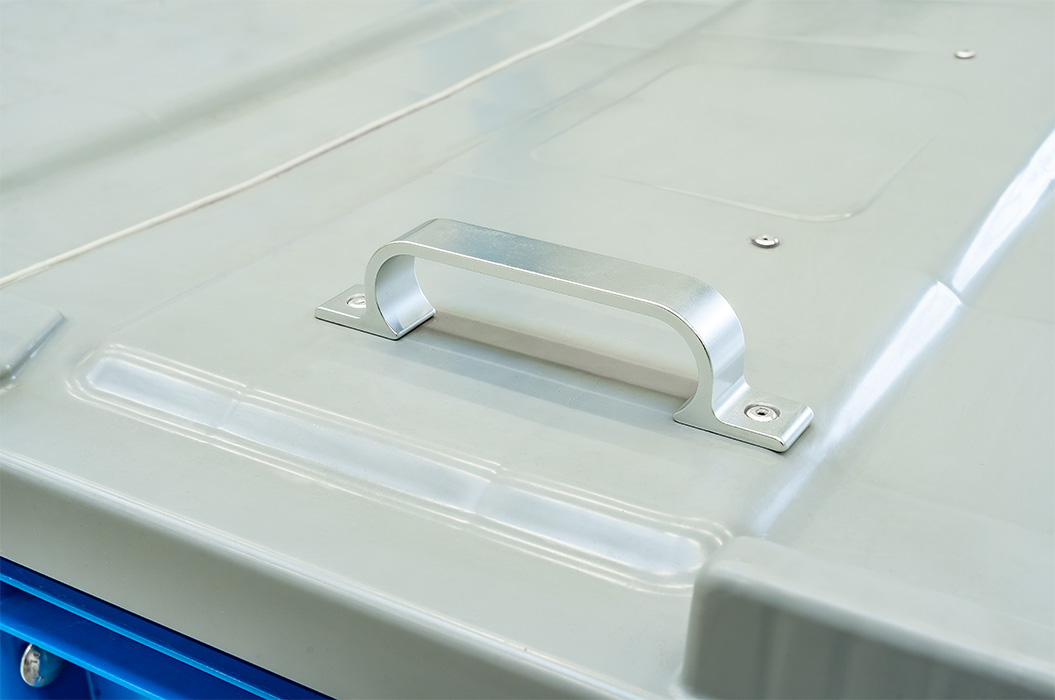 Ein grauer Metallgriff auf einem blau-grauen Containerdeckel.